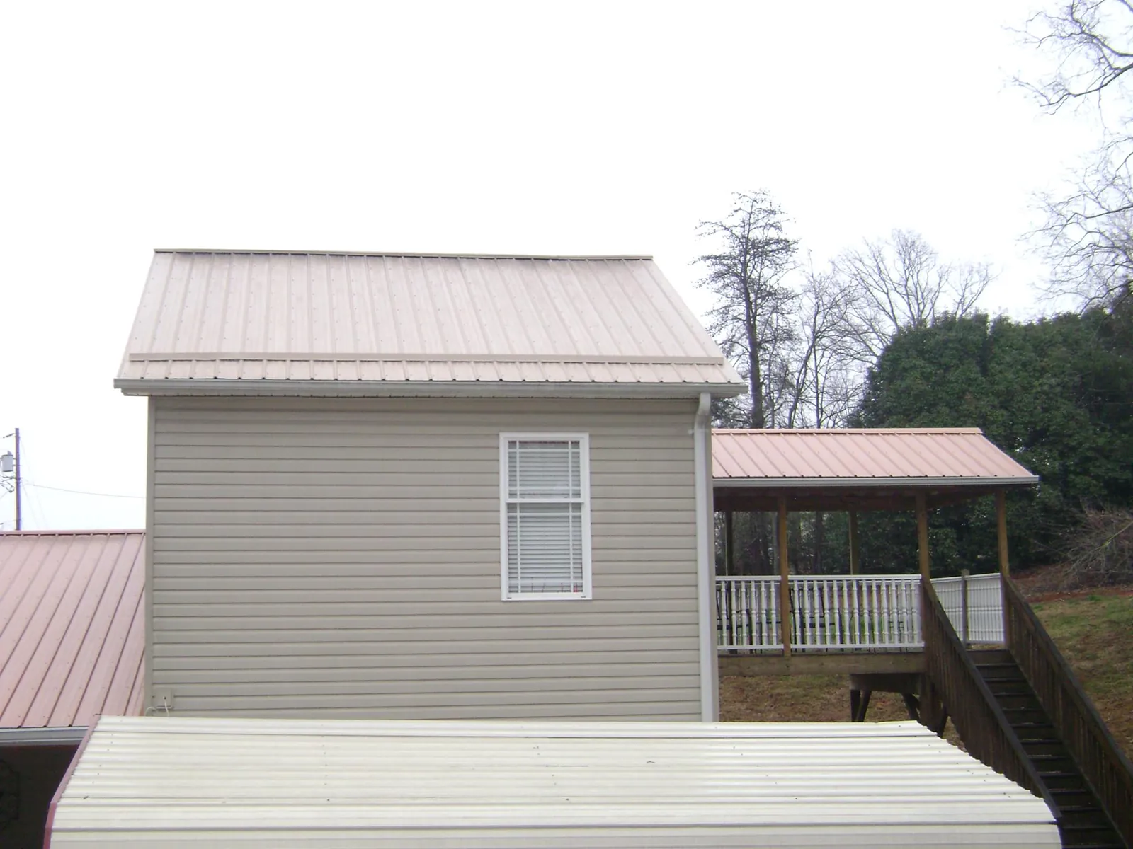 Tan metal roofs on a two story addition and attached porch, from a Roof Replacement job in Hazleton
